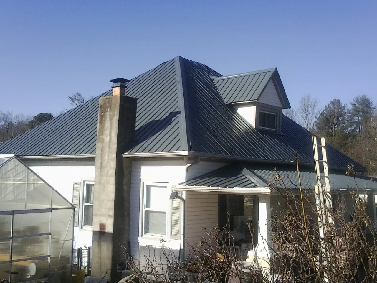 Dark blue standing seam metal roof on a white farmhouse with dormer — Slate & Tile Roof Repair by Roofing Brothers in Scappoose