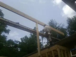 Carpenter setting a ridge beam over a new addition frame — Ice Dam Removal by Roofing Brothers in Scappoose