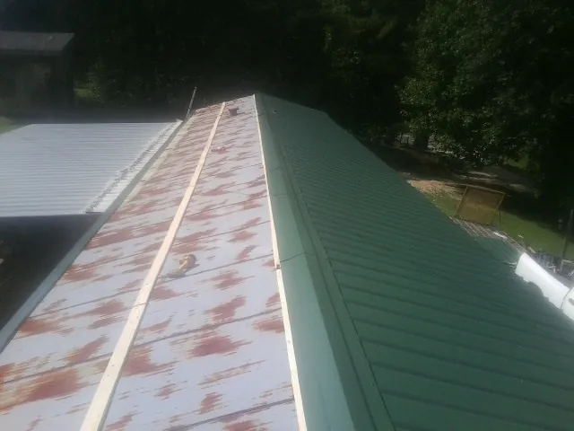 Old rusted panels beside newly installed green metal roofing — Wind Damage Roof Repair by Roofing Brothers in Scappoose
