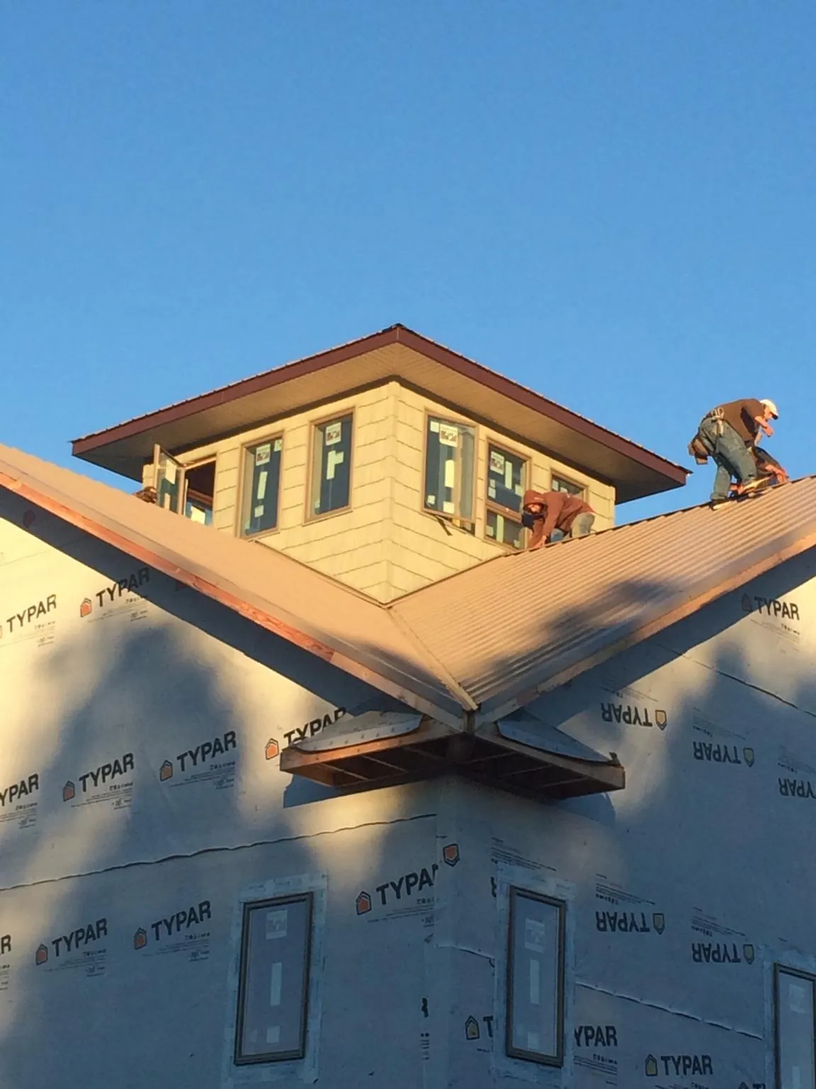 Roofers working around a rooftop cupola on a new metal roof at sunset — Roof Waterproofing in Scappoose by Roofing Brothers